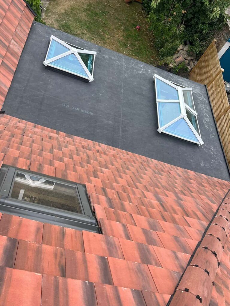 This is a photo taken from the roof ridge looking down a tiled pitched roof on to a flat roof. Works carried out by Broughton Astley Roofing Repairs